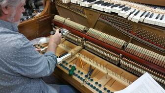 Piano technician repairing the internal action mechanism