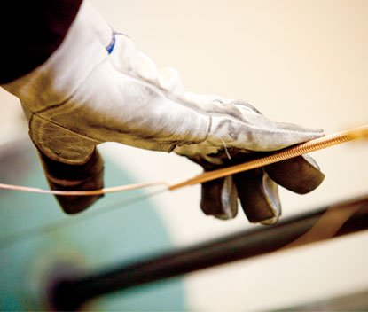 A craftsman hand-winding a piano bass string