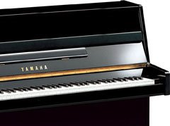 Close-up of a polished black Yamaha b Series upright piano keyboard.