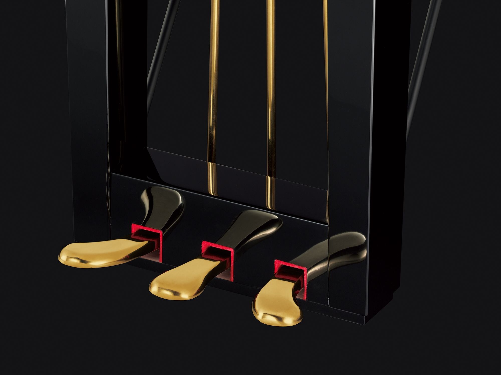 Three polished brass pedals and the black pedal lyre of a Yamaha CF Series grand piano