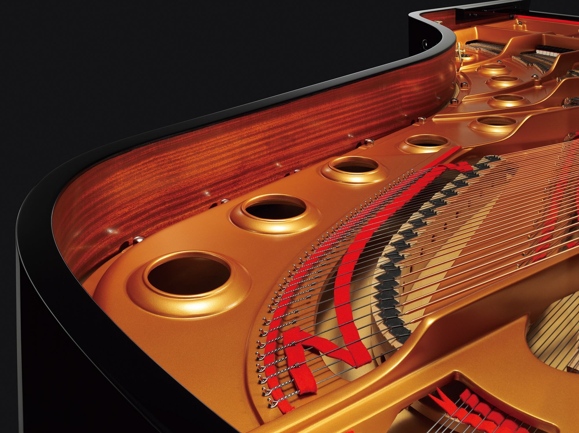 Gold-finished plate, strings, dampers, and wood inside a Yamaha grand piano