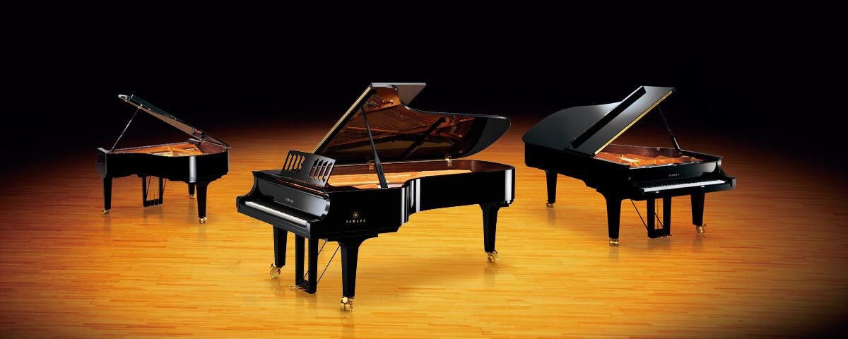 Three Yamaha CF Series grand pianos on a warm wooden stage