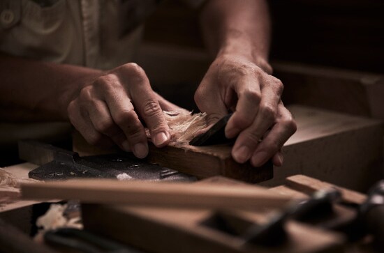 Craftsman shaping piano wood by hand