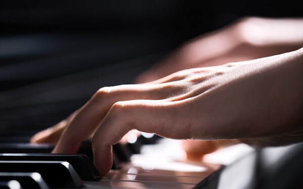 Hands playing the keys of a piano