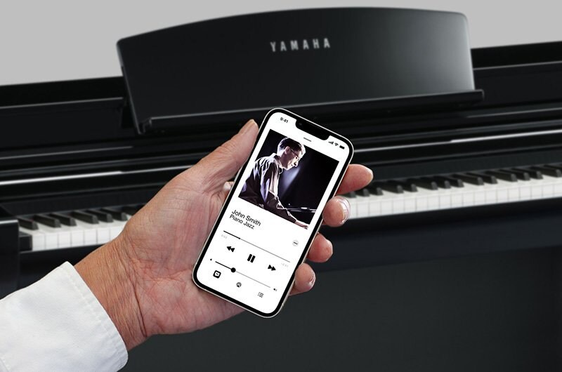 A smart device playing audio beside a Yamaha Clavinova piano