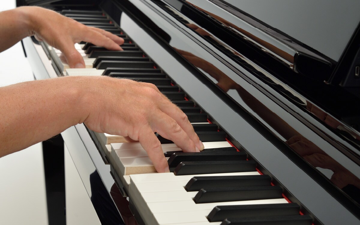 Hands playing the keys of a Yamaha Clavinova digital piano.