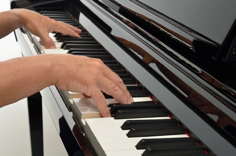 Hands playing the GrandTouch-S keyboard of a Yamaha Clavinova.