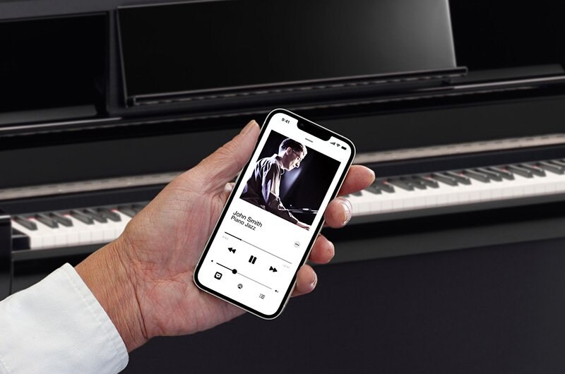 A smartphone playing audio in front of a Yamaha Clavinova piano.