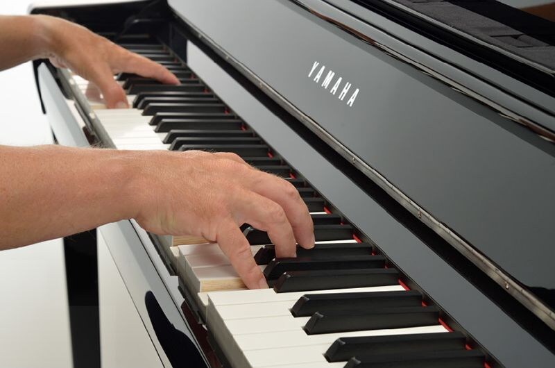 Hands playing the keys of a Yamaha Clavinova digital piano.