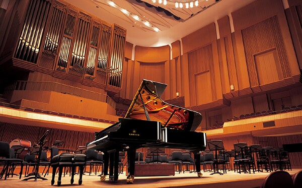 A grand piano on a concert hall stage.