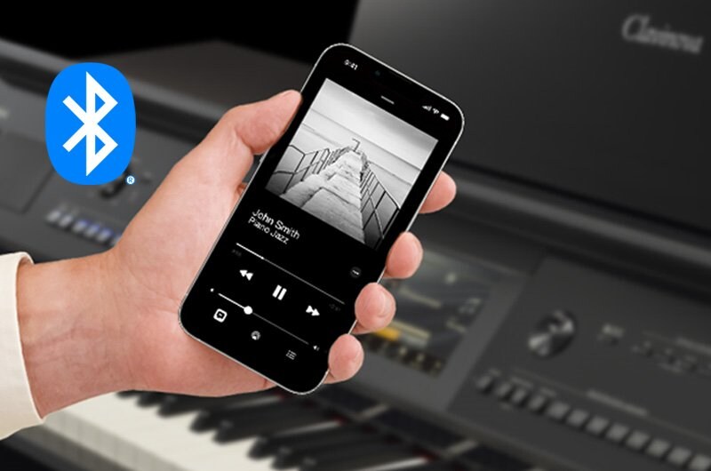 A smartphone showing music playback beside a Yamaha Clavinova