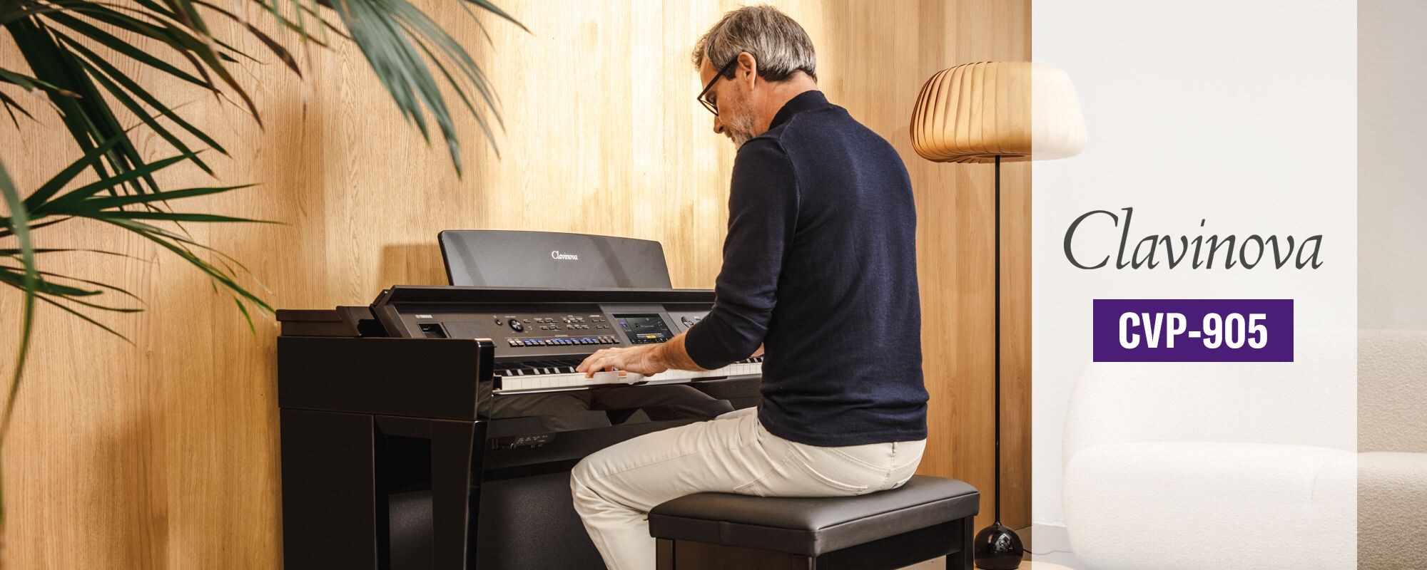 A person playing a Yamaha CVP-905 Clavinova in a warm modern room