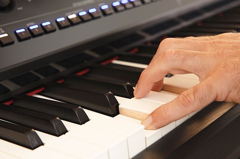 Hand playing the Yamaha Clavinova GrandTouch keyboard.