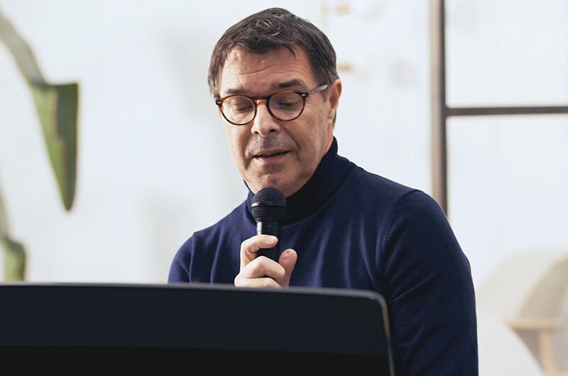 Man singing with a microphone beside a Yamaha Clavinova piano.