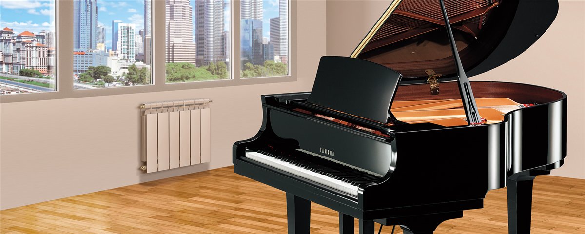 Black Yamaha CX Series grand piano in a light-filled room with a city view