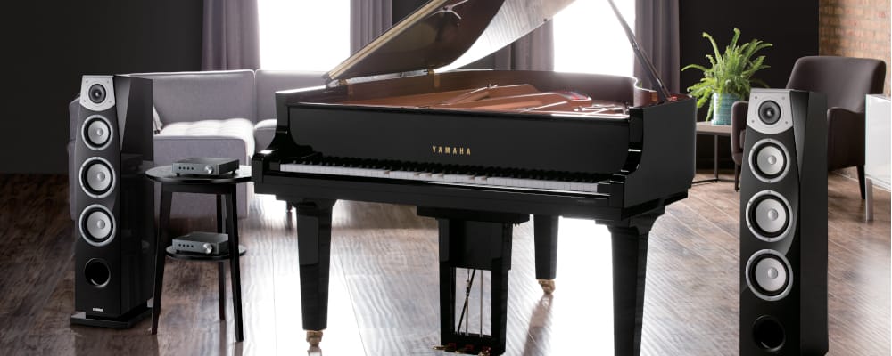Yamaha Disklavier piano with Yamaha speakers in a living room.