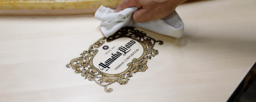 Yamaha Piano logo being polished by hand.