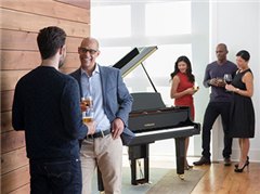 People socializing in a living room with a Yamaha Disklavier grand piano