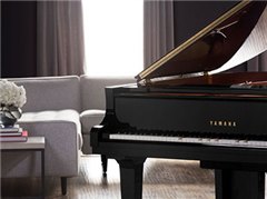 Black Yamaha Disklavier grand piano in a modern living room next to a light-colored sofa
