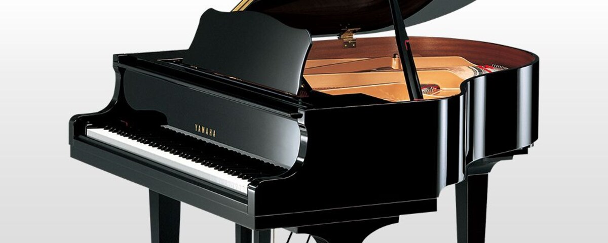 Studio photograph of a black Yamaha GB1K grand piano with its lid open.