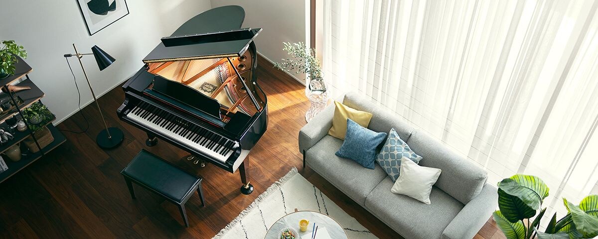 High-angle view of a polished black Yamaha grand piano in a bright, modern living room.