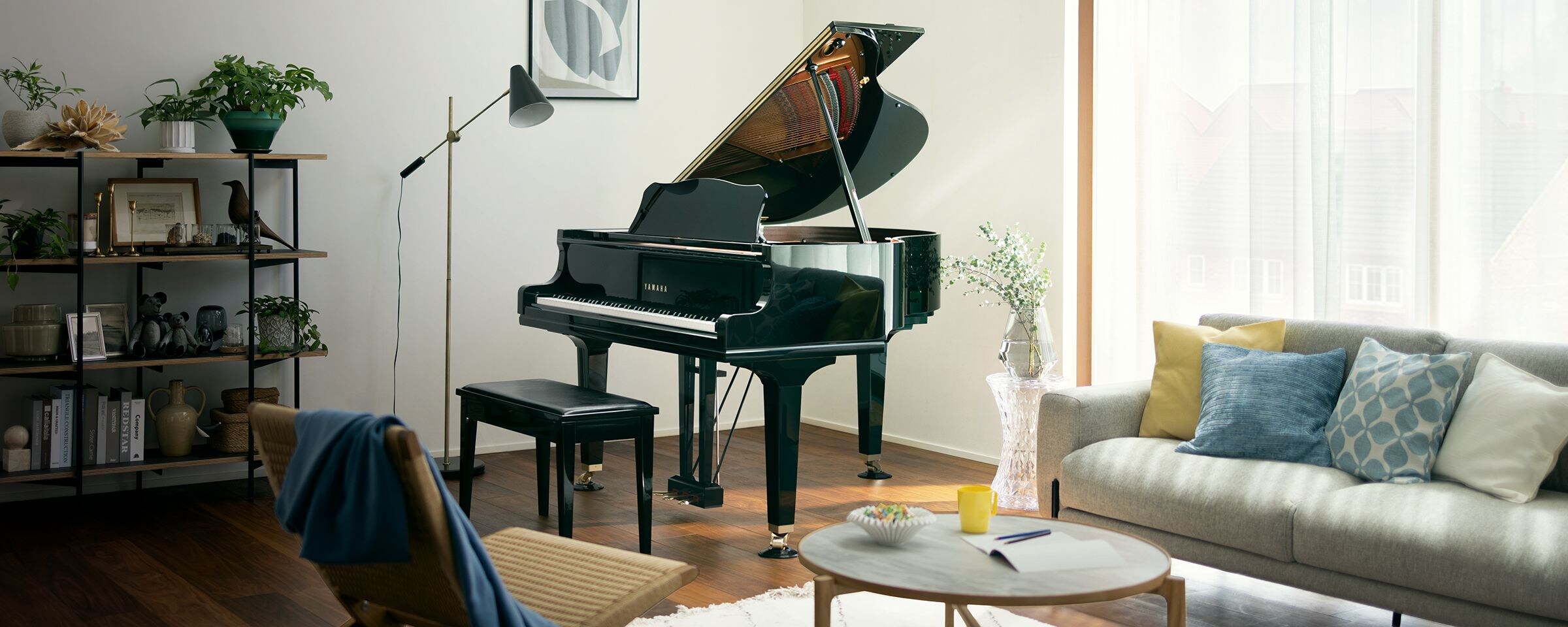 Glossy black Yamaha grand piano with its lid open in a bright, modern living room.