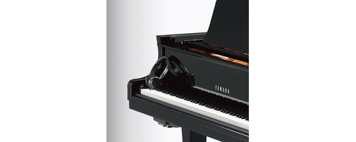 Black headphones resting on the keyboard of a Yamaha grand piano.