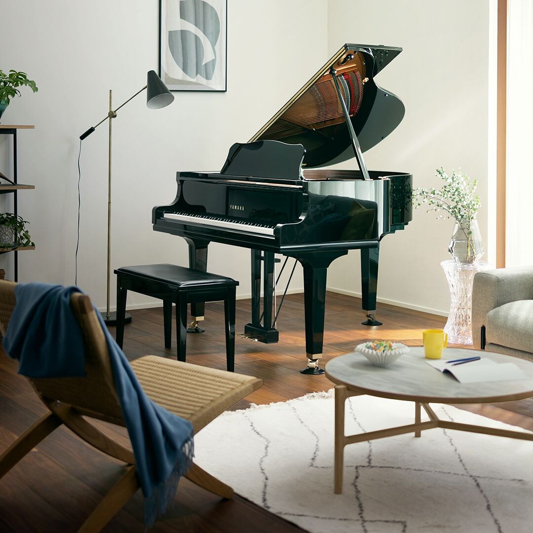 Glossy black Yamaha grand piano centered in a bright, modern living room.