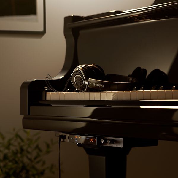 Black headphones and a SILENT Piano system control module on a Yamaha grand piano.