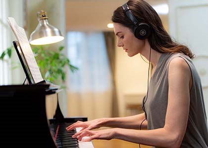 Woman playing Yamaha N1X piano while wearing headphones.