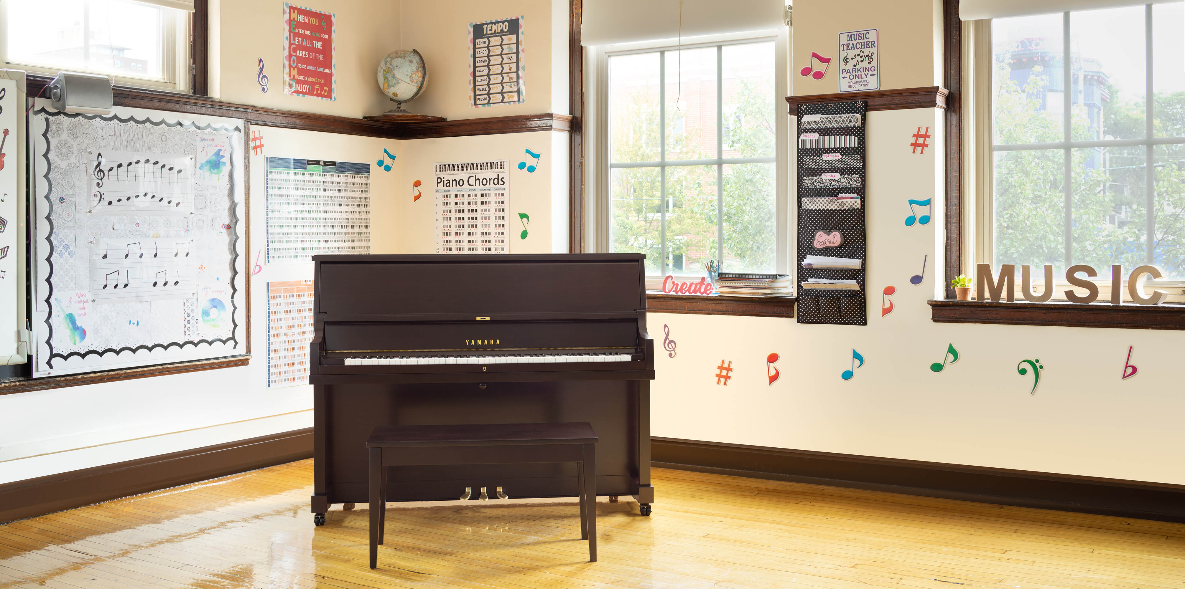A Yamaha P22 upright piano with a bench in a music classroom.