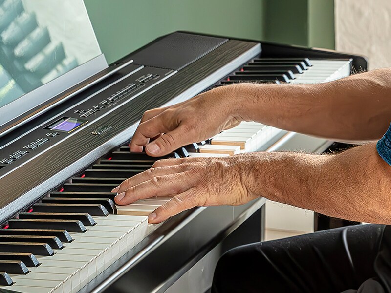 A person playing the Yamaha P-525 portable piano