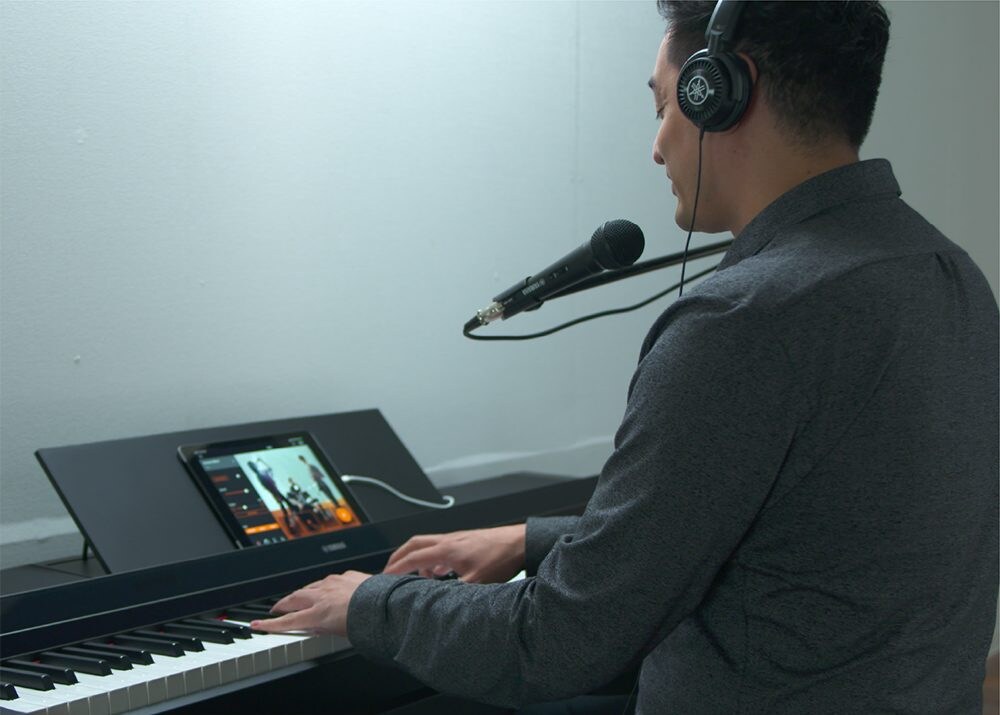 A person singing and playing a Yamaha P-S500 digital piano