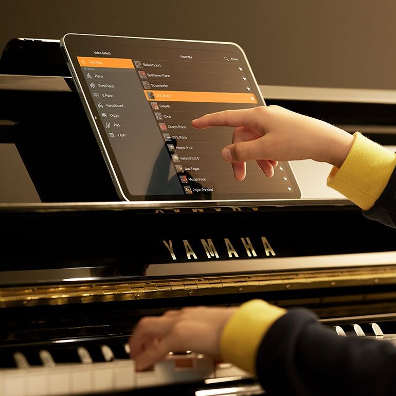 The Smart Pianist app displayed on a tablet beside a Yamaha piano.